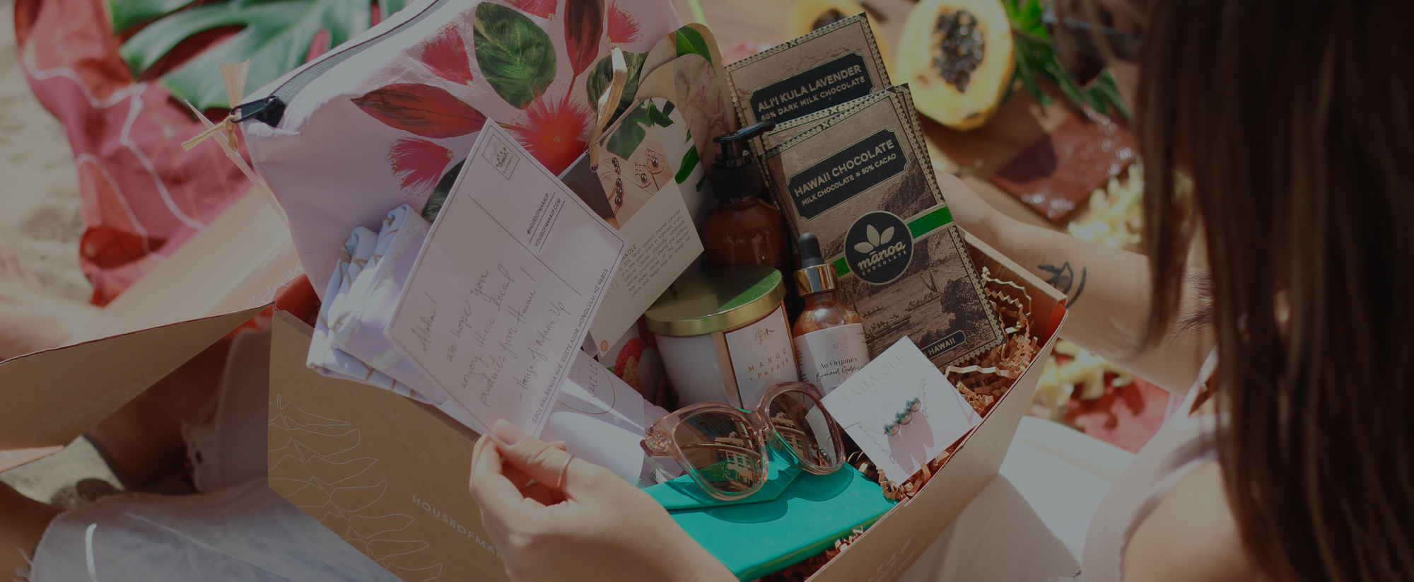 Woman going through a hawaiian gift box full of different items