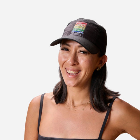 Woman wearing a black cap with a colorful logo on a white background