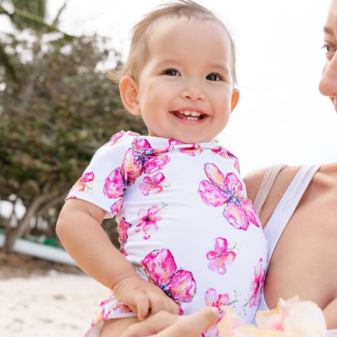 baby smiling in white and pink onesie