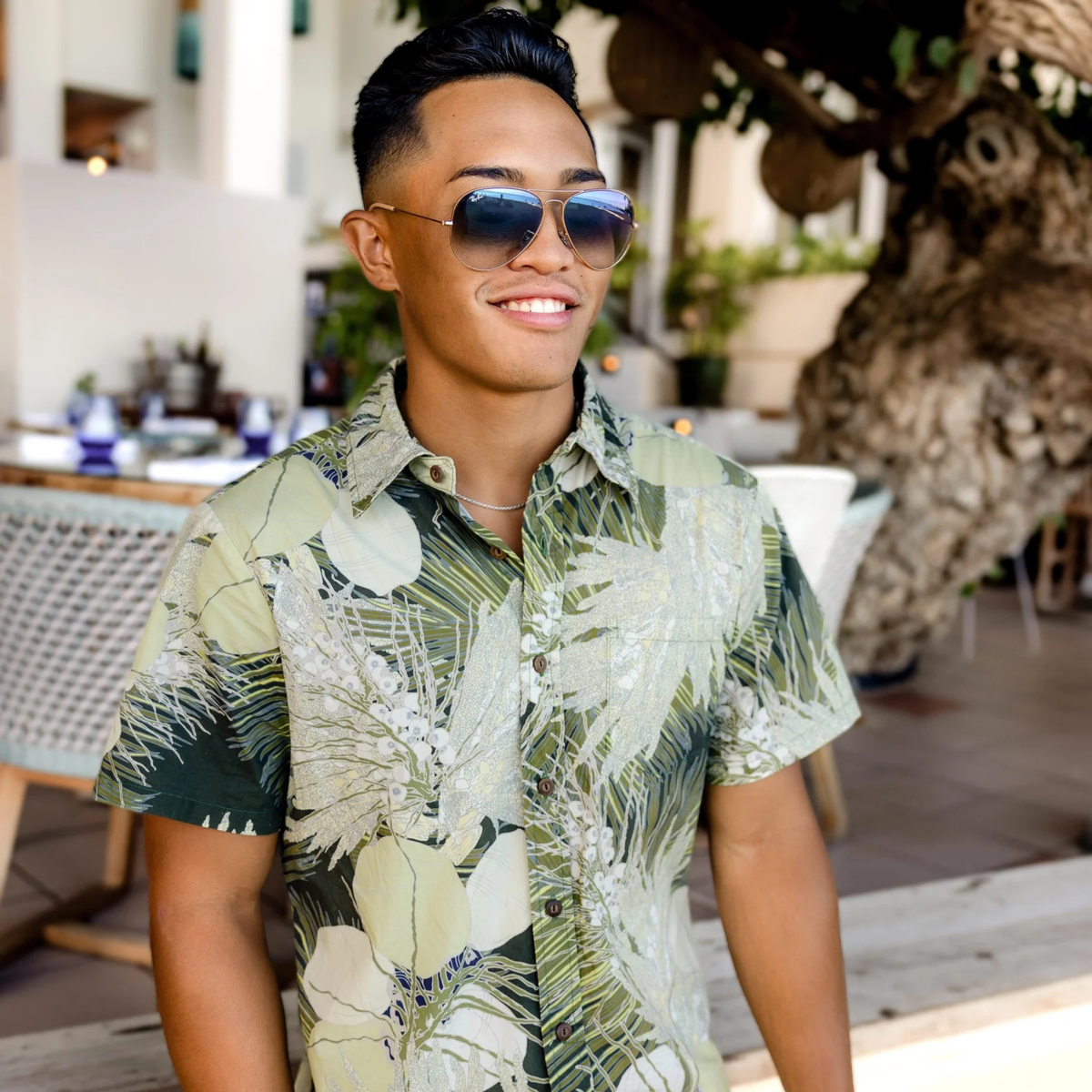 Man wearing a tropical shirt and sunglasses in an outdoor setting