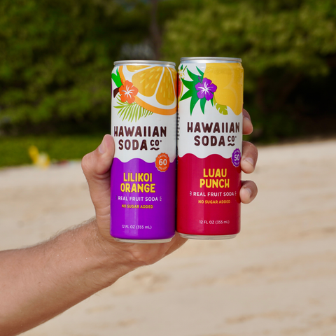 Two cans of Hawaiian Soda Co. on a beach
