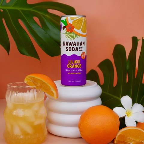 Hawaiian Soda Co. Lilikoi Orange soda can with a glass of orange juice and oranges on a colorful background