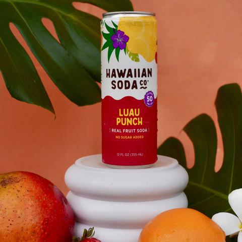 Hawaiian Soda Co. Luau Punch can on a white pedestal with fruits and leaves in the background