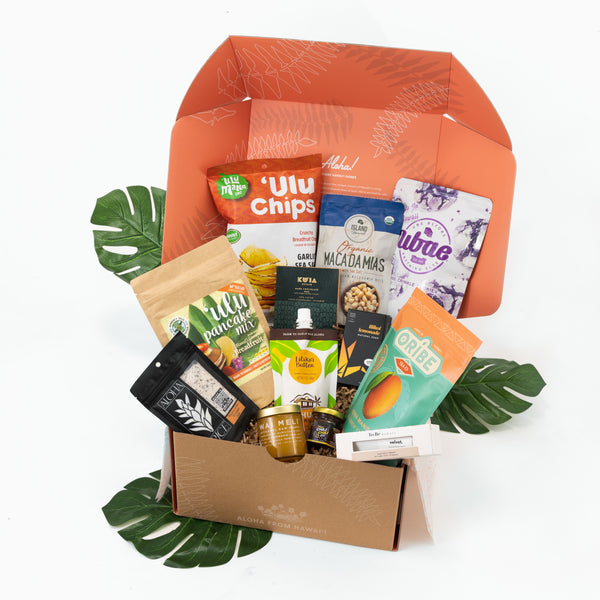 Assorted snack items in a box with decorative leaves on a white background