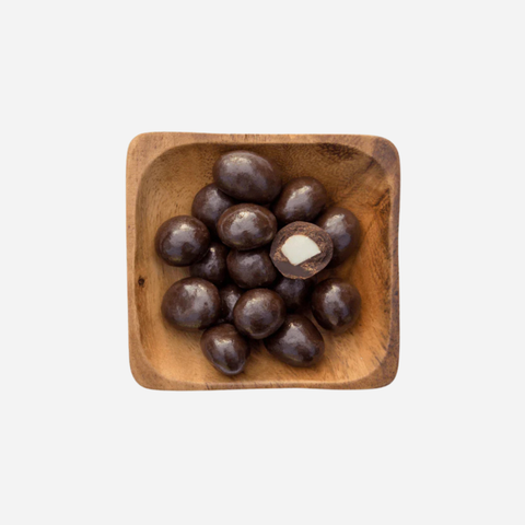 Wooden bowl filled with dark chocolates on a white background