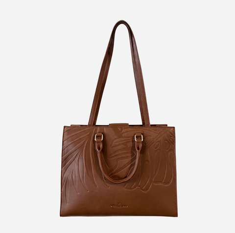 A brown leather tote bag with embossed floral details and double top handles, shown against a plain light gray background.