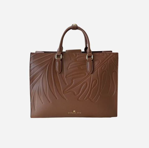 A brown leather tote bag with embossed leaf patterns and dual top handles, shown against a plain light gray background.