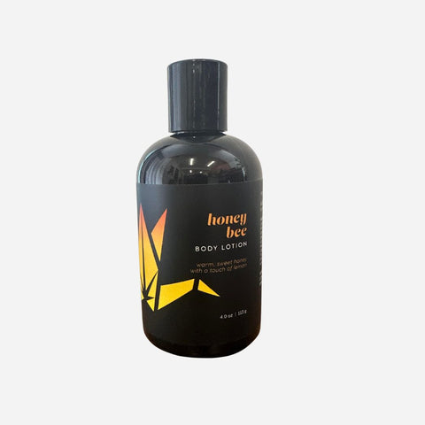 Black bottle of honey bee body lotion on a white background