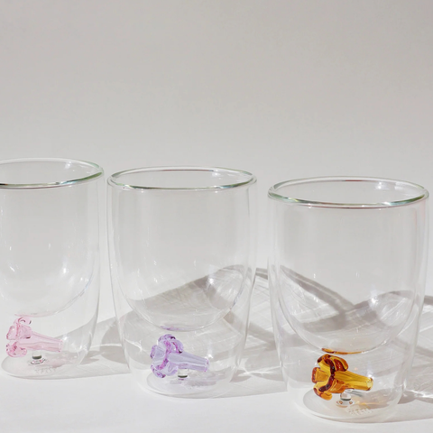 Set of three clear glass tumblers with colorful animal figurines on a white surface.