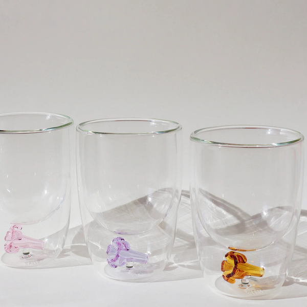 Set of three clear glass tumblers with colorful animal figurines on a white surface.