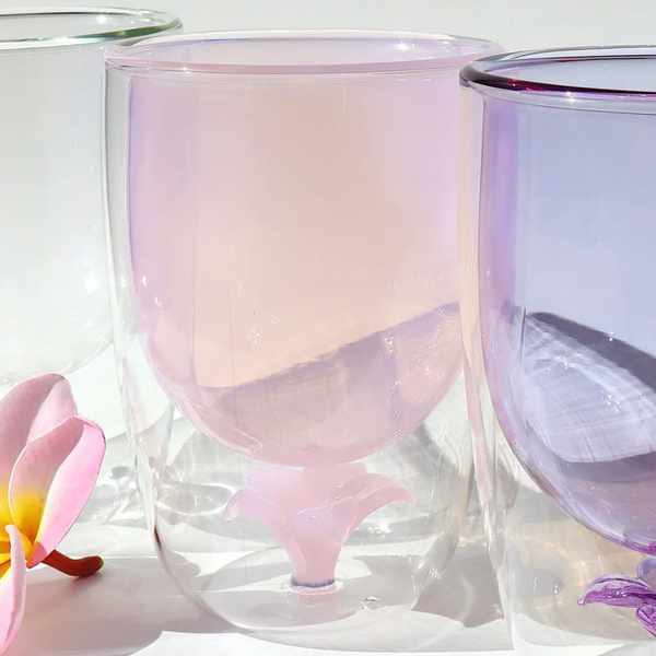 Set of three gradient glass tumblers with a pink and purple color scheme, accompanied by a frangipani flower.