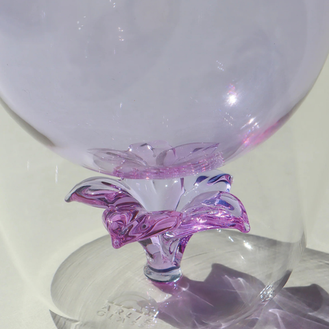 Clear glass goblet with pink decorative base on a white background