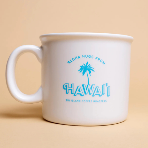 White mug with blue text and palm tree design on a beige background