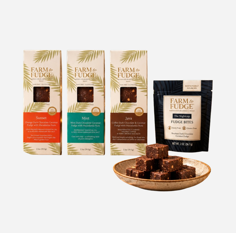 Four Farm to Fudge product boxes and a stand-up pouch of Fudge Bites arranged on a light gray background, with a small plate of chocolate fudge cubes in front.