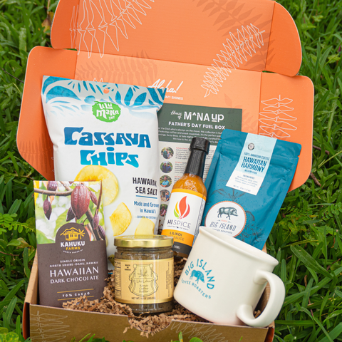 Gift box with various Hawaiian products including chips, coffee, and chocolate on grass