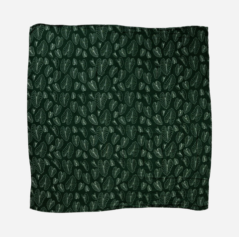 A square bandana featuring an all-over repeating pattern of light green tropical leaf silhouettes on a dark forest green background, displayed flat against a light gray backdrop.