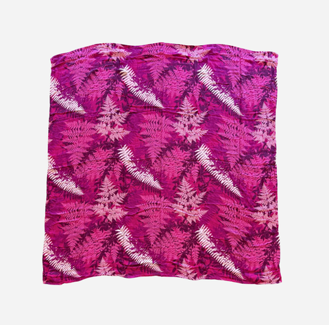 A square scarf featuring a vibrant magenta and pink fern pattern with white accents, laid flat against a light gray background.