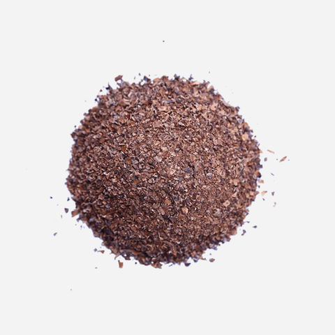A small mound of dark brown ground coffee beans or coffee powder on a plain white background.