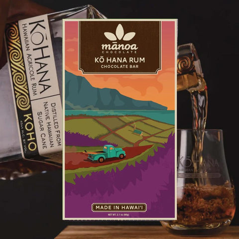 Manoa Köhana Rum chocolate bar packaging with a scenic design, next to a glass of rum.