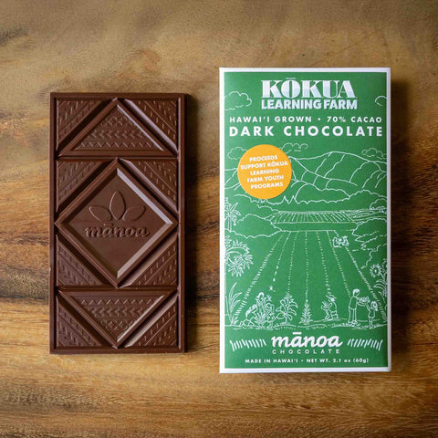 Dark chocolate bar with a green Kokua Learning Farm packaging on a wooden surface