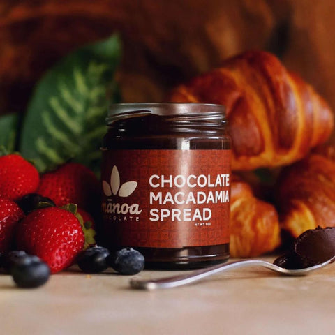 Jar of chocolate macadamia spread with berries and croissants in the background