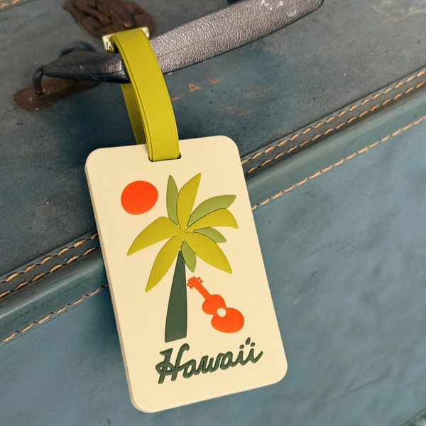 Luggage tag with palm tree and ukulele design on a suitcase