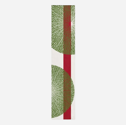 A tall, narrow rectangular scarf featuring a modern geometric pattern with green radiating leaf-like shapes, a vertical red stripe, and a white center band on a light gray background.