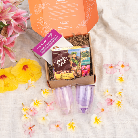 Hawaiian themed gift set with flowers and a box on a textured surface