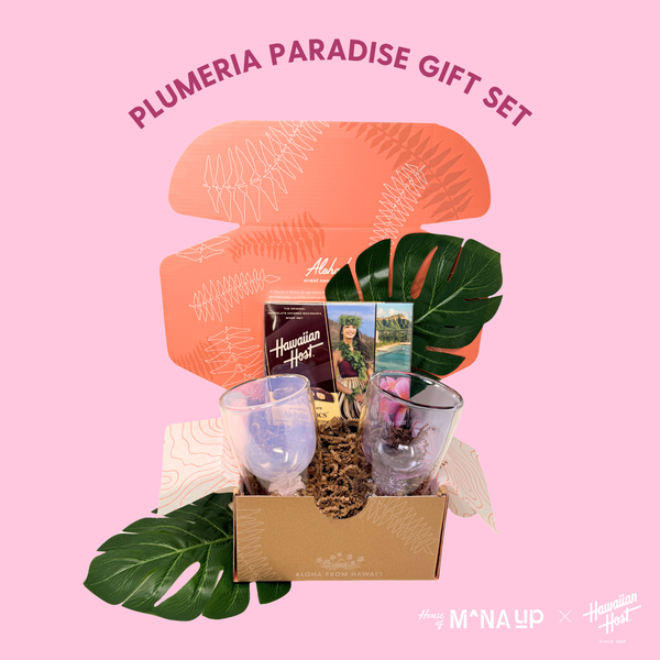 Plumeria Paradise gift set with two glasses, a book, and decorative items on a pink background.