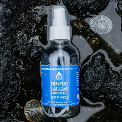 Bottle of Pure Hawaii Deep Ocean Magnesium Mist with a blue label on a dark, textured background.