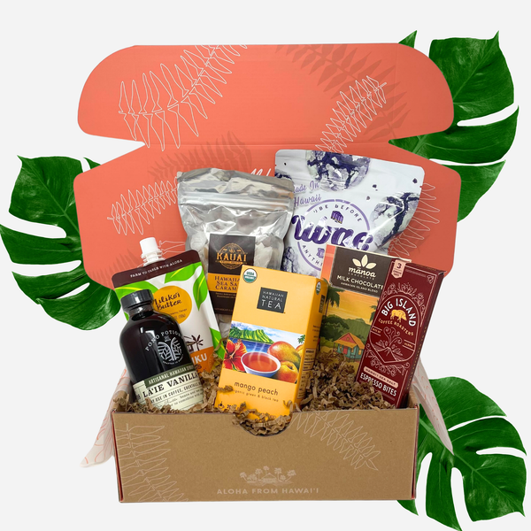 Gift box with assorted products including tea and chocolate, surrounded by decorative leaves.