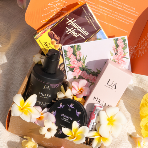 Assorted skincare products and flowers in a decorative box with 'Hawaiian Host' branding.