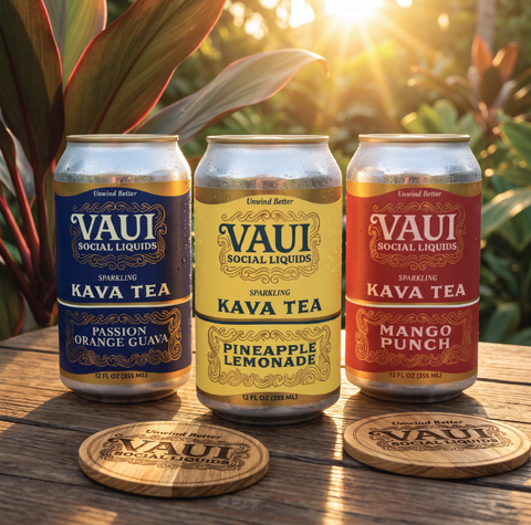 Three cans of VAUI Social Liquids sparkling kava tea are arranged on a wooden surface outdoors with warm sunlight and tropical leaves in the background. The cans are labeled Passion Orange Guava, Pineapple Lemonade, and Mango Punch, with matching branded coasters in front.