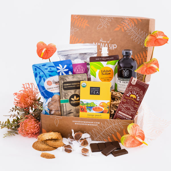 A gift basket with an assortment of sweet Hawaiian treats including chocolate bars, coffee bites, tea bags, passionfruit butter, vanilla syrup, cookies, and caramel candies.